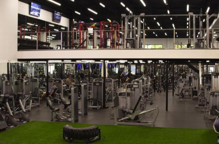Personal trainer spotting a man with weights.